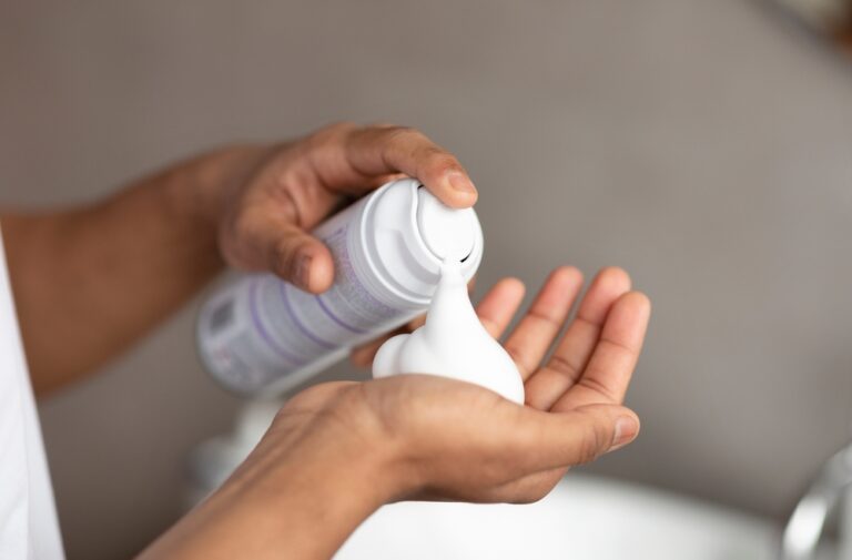 Man spraying white shaving cream into his hand