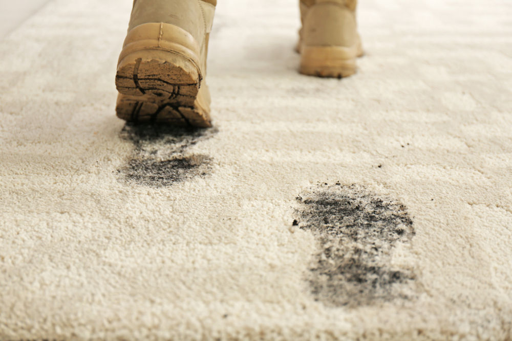 Dirty boots leaving footprints on light carpet